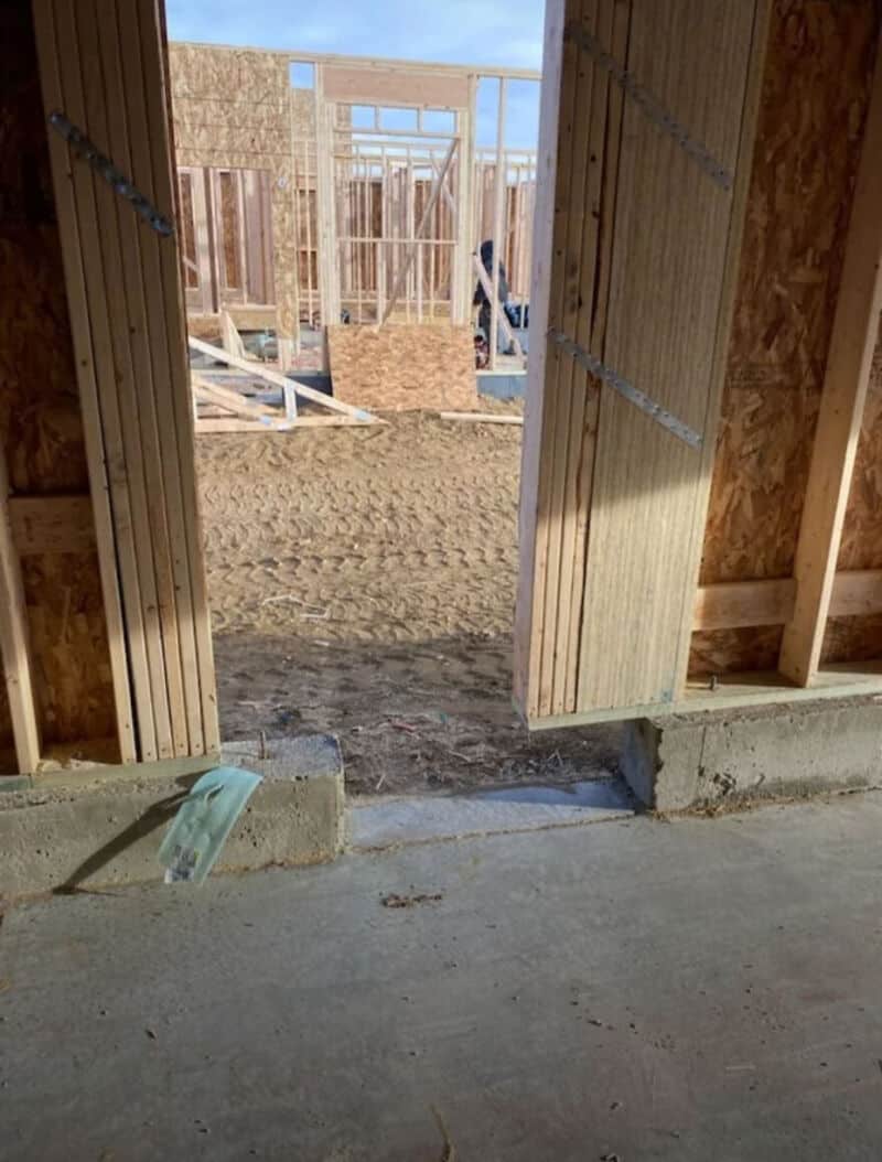 View through doorway of a construction site with framing and blue sky.