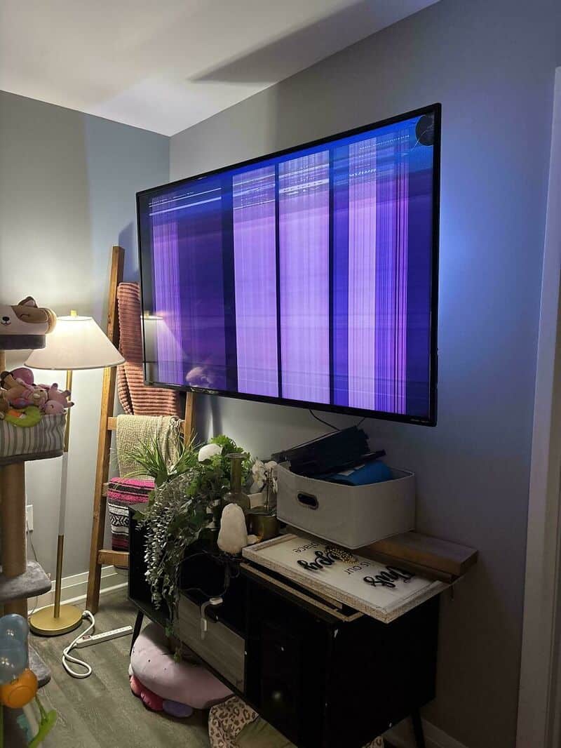 Flat-screen TV with vertical purple and blue lines, screen damaged.