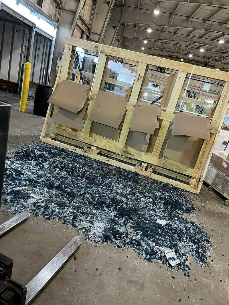 Damaged wooden crate with broken glass and debris on the floor.