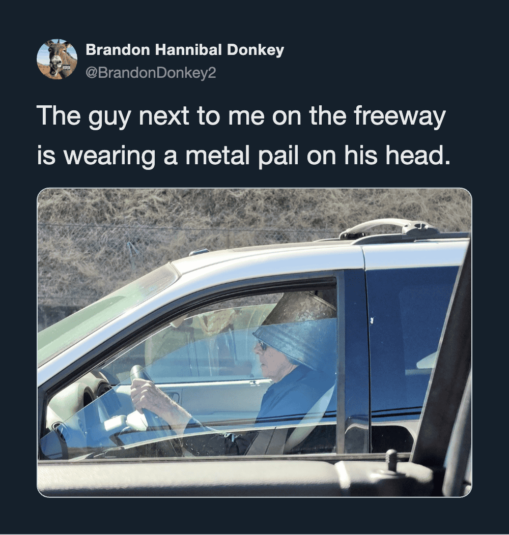 Man with metal pail on head driving on freeway, humorous tweet.
