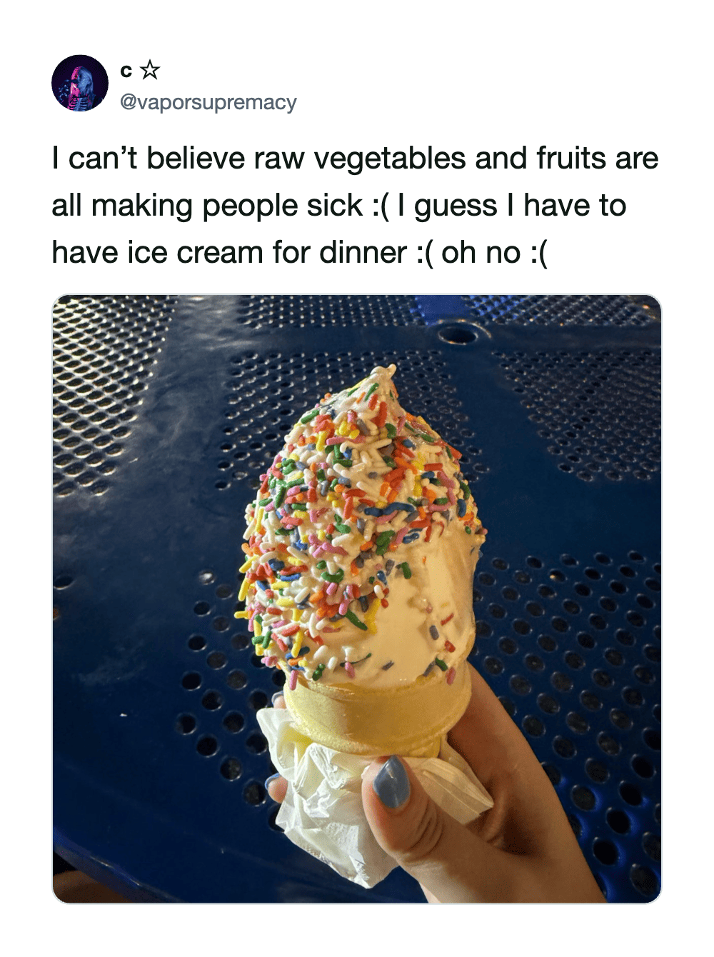 Ice cream cone with colorful sprinkles, held by a hand with painted nails.