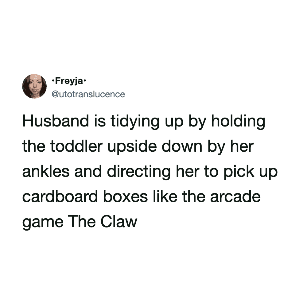 Husband tidying up by holding toddler upside down by her ankles, directing her to pick up cardboard.