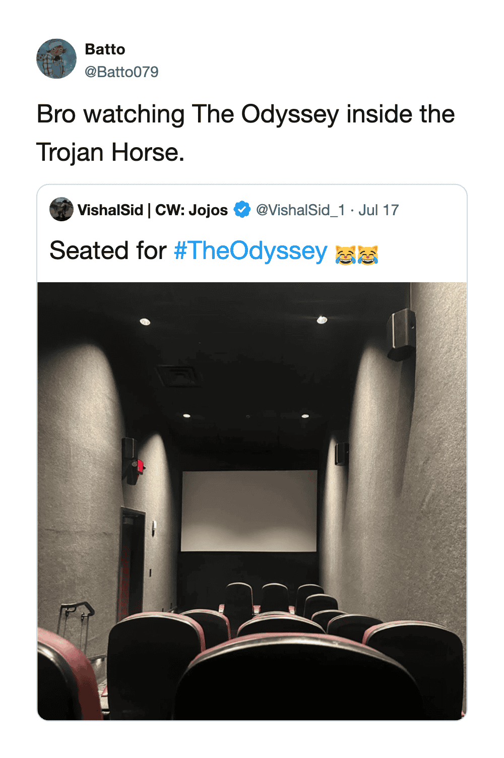 A movie theater with empty seats and a large screen, viewed from the back.