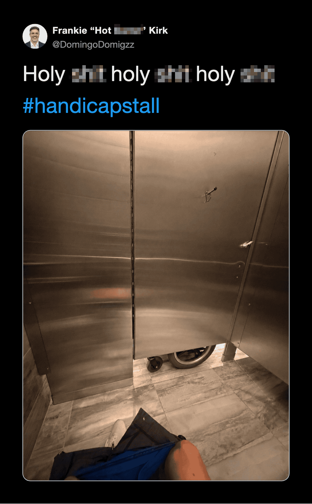 Person's leg and shoe near a bathroom stall door with a wheel underneath.