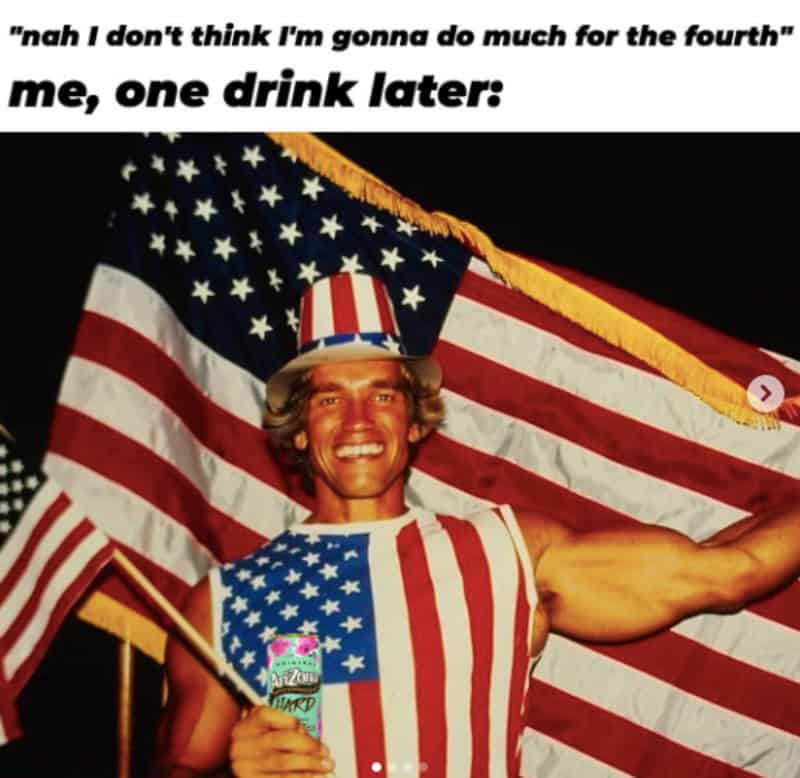 Man in patriotic outfit holding a drink, with American flag background, celebrating July 4th.