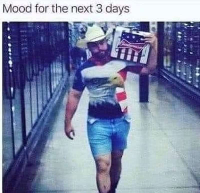 Person walking with a flag-themed bag, wearing a hat, in a store aisle.