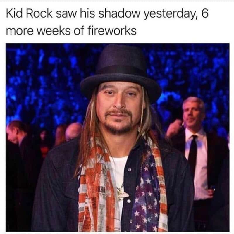 Kid Rock at an event with a hat, long hair, and an American flag scarf.
