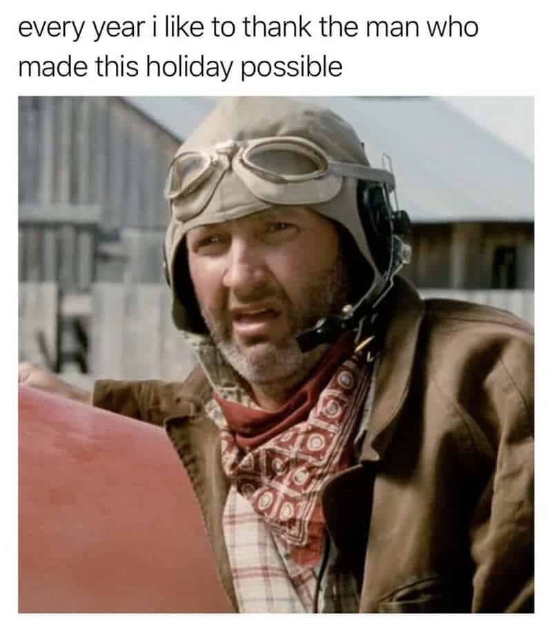 Man in vintage pilot gear with goggles and scarf, looking to the side.