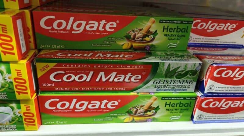 Two boxes of Colgate herbal toothpaste and a Cool Mate herbal toothpaste box on a store shelf.
