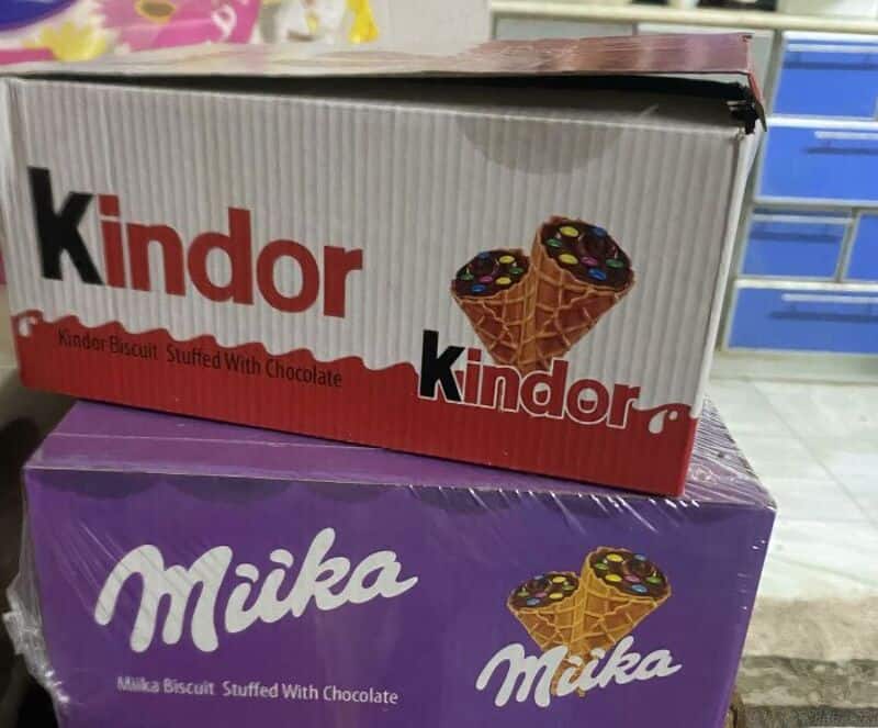 Kinder and Milka biscuit boxes with chocolate, stacked on a shelf.