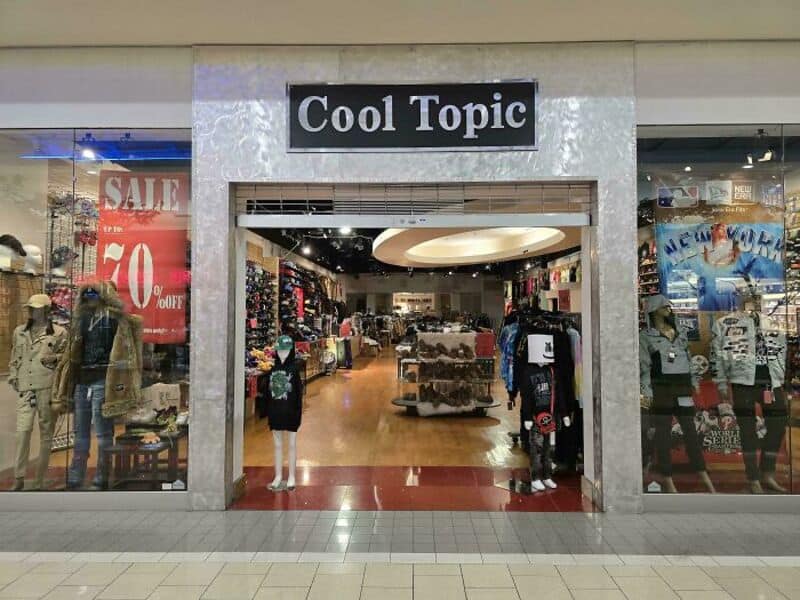 Store entrance with 'Cool Topic' sign, mannequins, sale sign, and clothing displays.