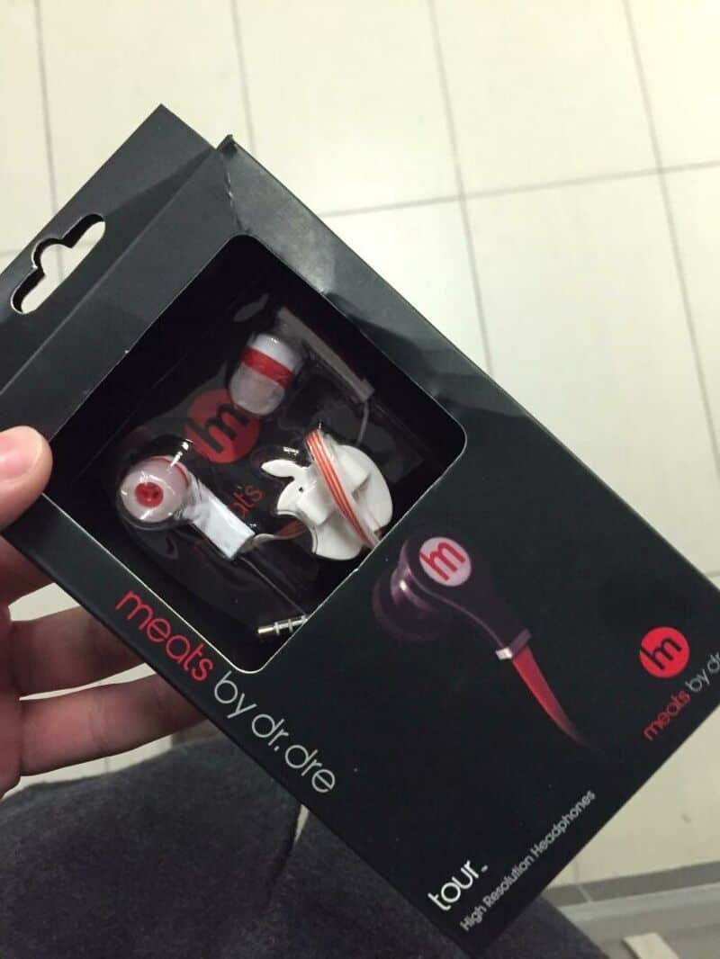 Earphones with a red and white design in a black box, labeled 'meets by dr. dre'.