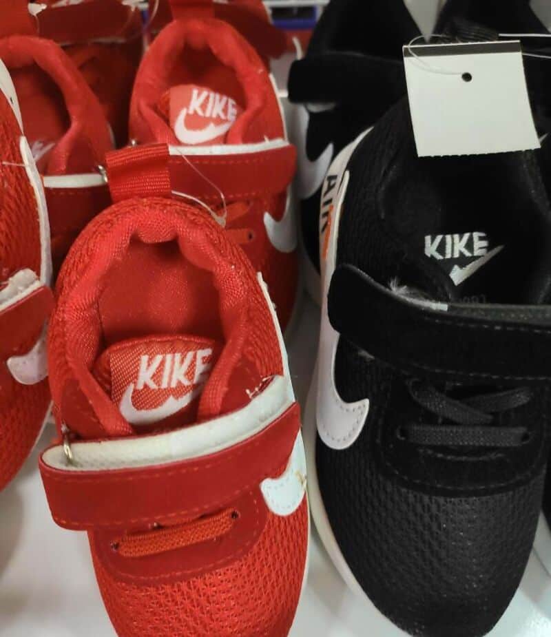 Red and black Nike knockoff sneakers side by side on display.