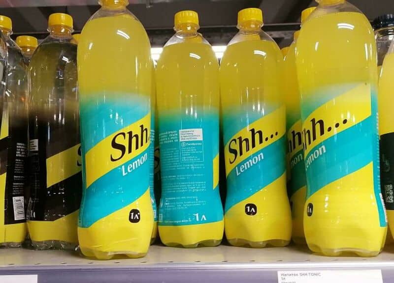 Bottle of lemon-flavored drink with a label reading 'Shh... Lemon' on a store shelf.