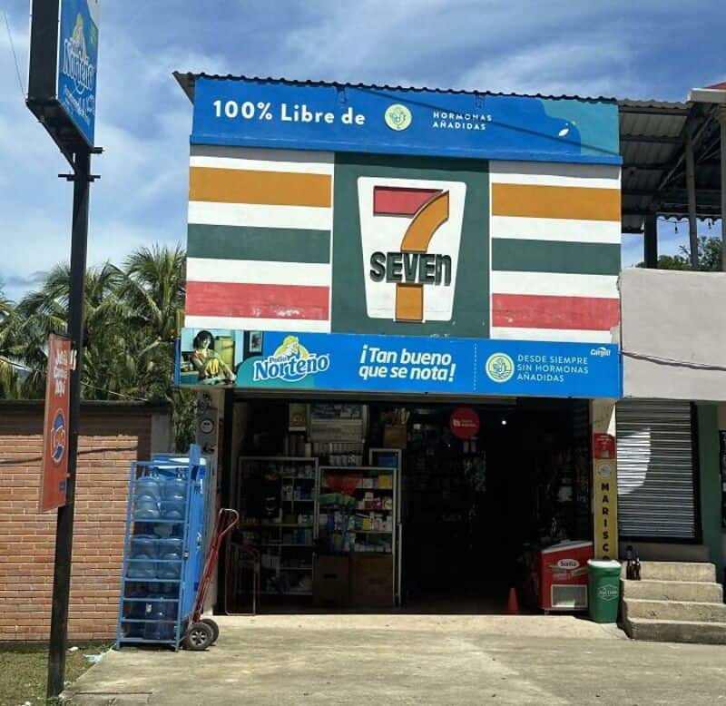 Store with a sign for '7 SEVEN' and advertisements for Hormonas Anádidas and Norteño.