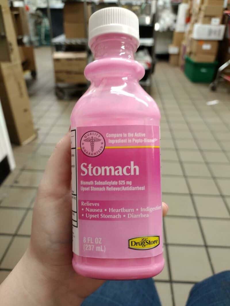 Pink bottle labeled 'Stomach' with drug store logo, in a store aisle.