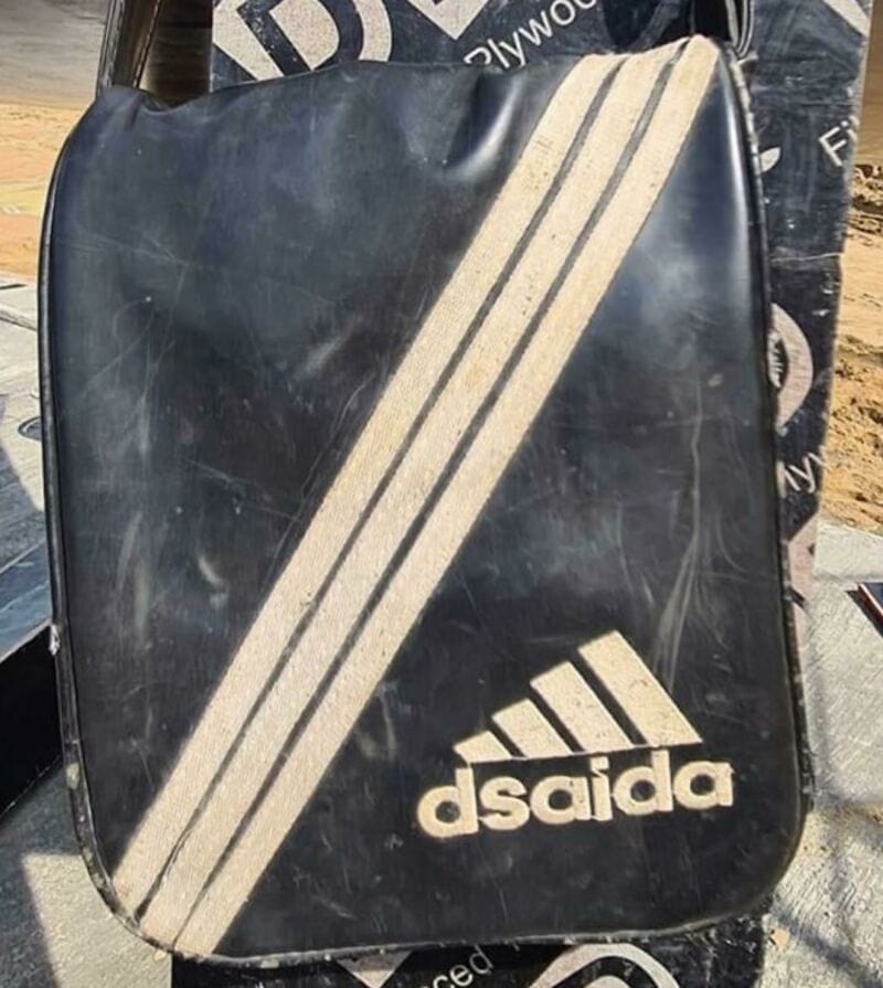 A black bag with a white Adidas logo and three white stripes.