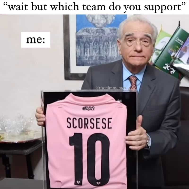 Man holding a framed pink soccer jersey with 'SCORSESE 10' on it, in an office.