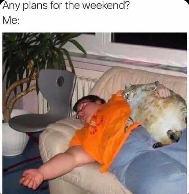 A boy sleeping on a couch with a cat lying on his back.