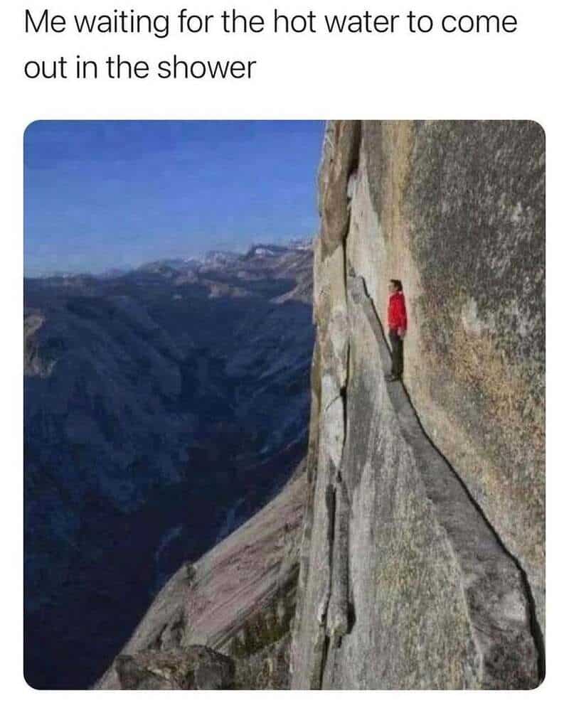Person waiting on a narrow mountain ledge for water to come out of a shower.
