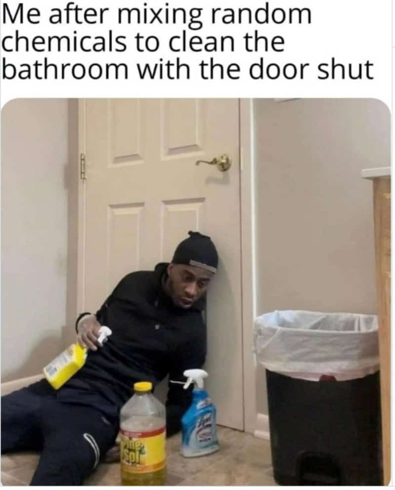 Man sitting on the floor with cleaning supplies near a bathroom door.