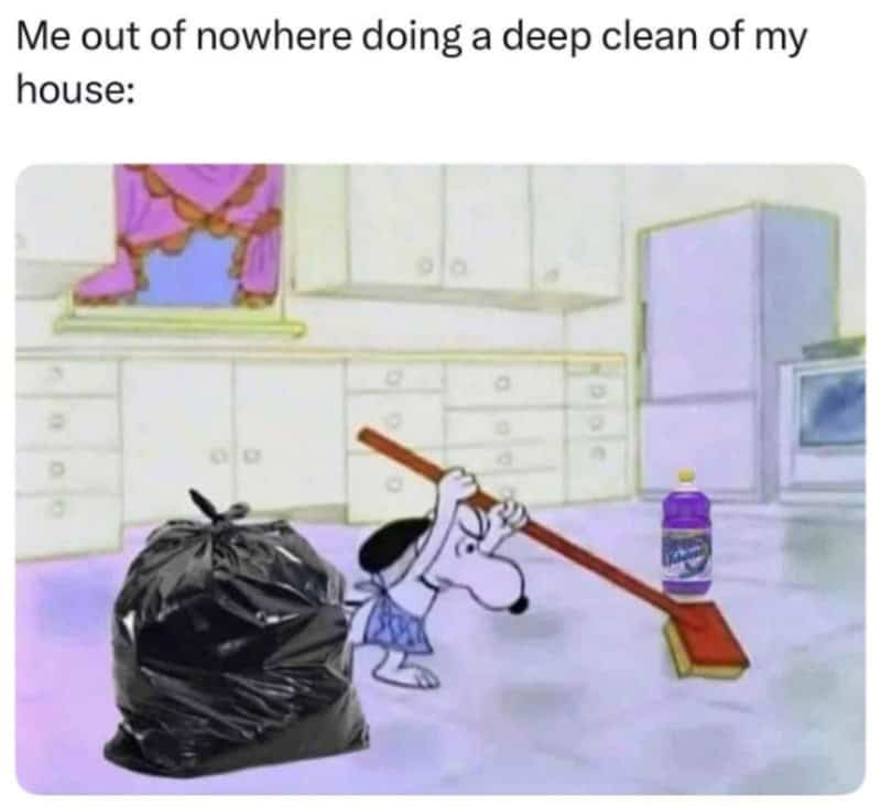 Dog sweeping the floor with a broom, a trash bag nearby, and a bottle on the floor.