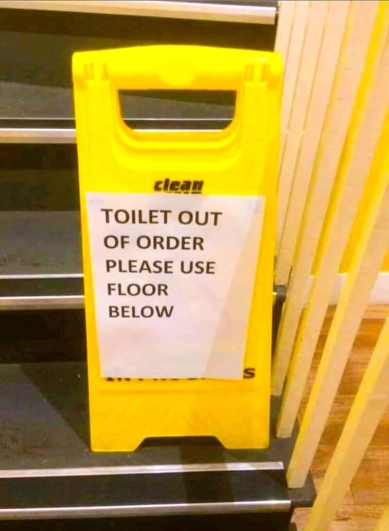 Yellow sign says 'TOILET OUT OF ORDER PLEASE USE FLOOR BELOW'.