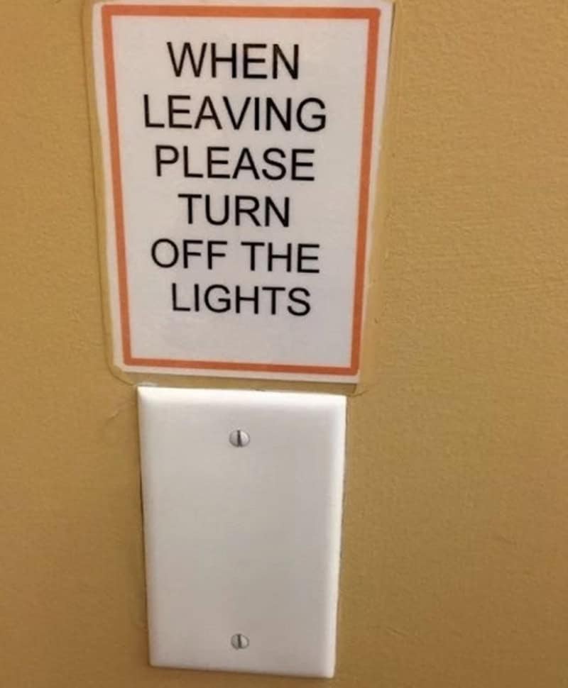 When leaving please turn off the lights sign on a yellow wall.