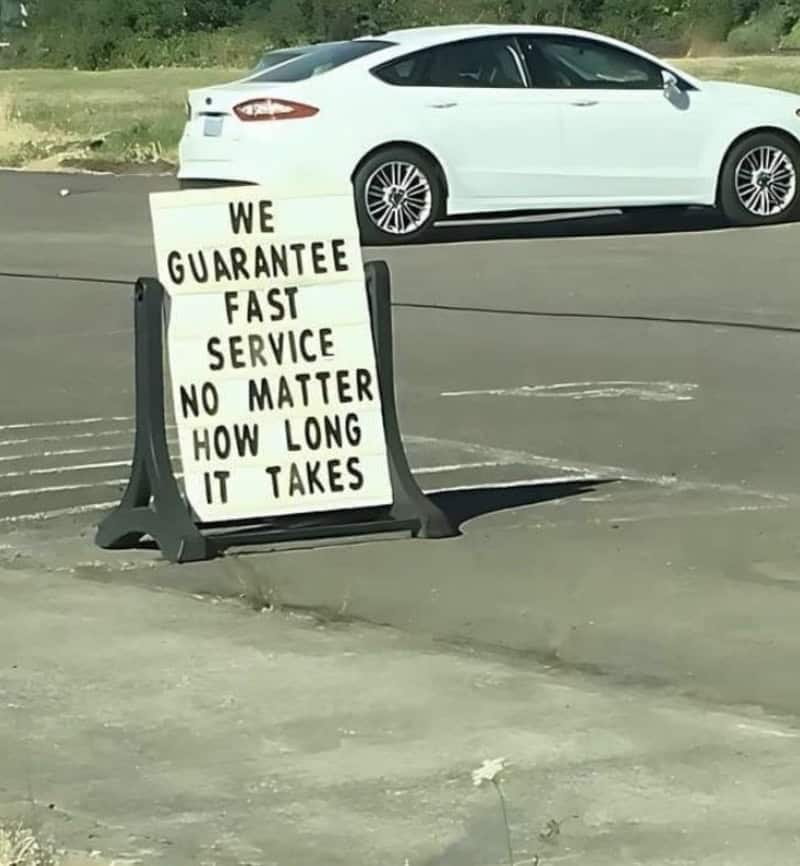 Sign in parking lot says: We guarantee fast service no matter how long it takes.