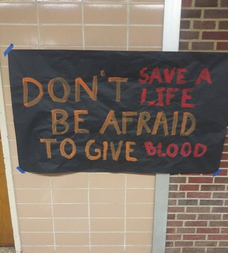 Sign reads 'DON'T BE AFRAID TO GIVE BLOOD' with 'SAVE A LIFE' in red.