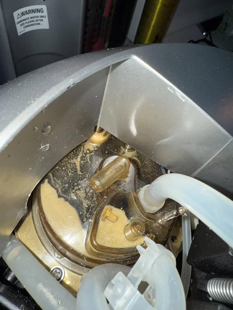 Close-up of a machine with a clogged filter and spilled debris inside.