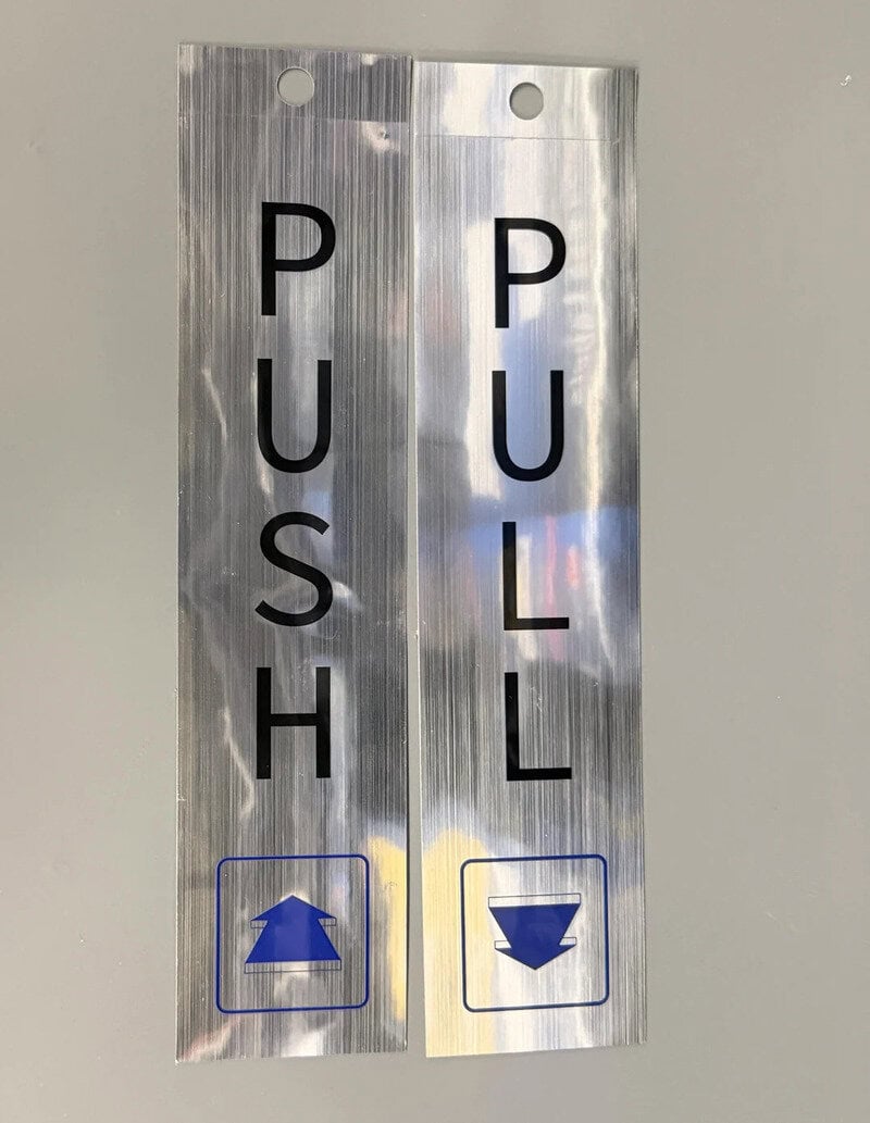 Push and pull buttons on a metallic panel with arrows indicating direction.