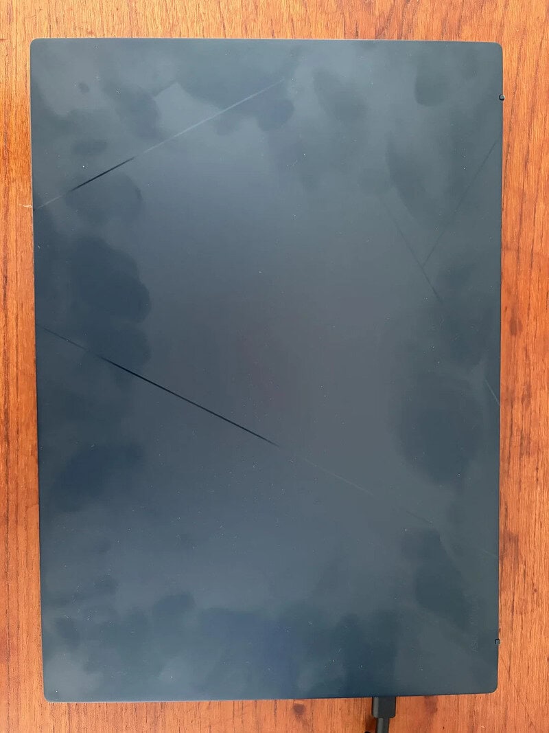Black electronic device with cracks on the surface on a wooden table.