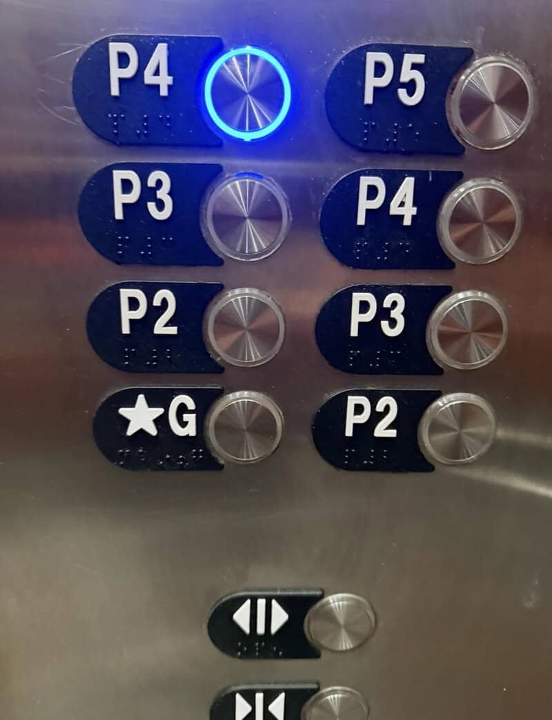 Elevator control panel with blue P4 button and illuminated ring, other buttons labeled P2 to P5 andG.