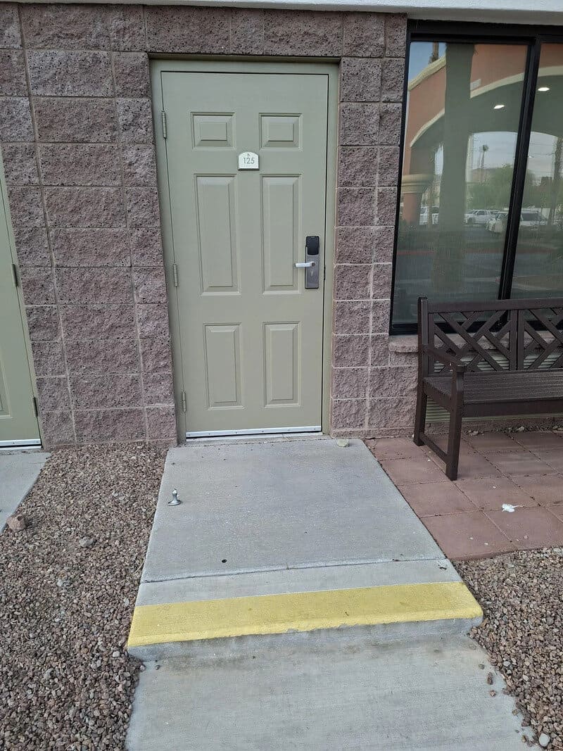 Door with a ramp and a yellow strip at the bottom, outside a building.