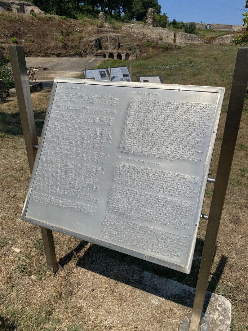 Information board with text at an outdoor archaeological site.