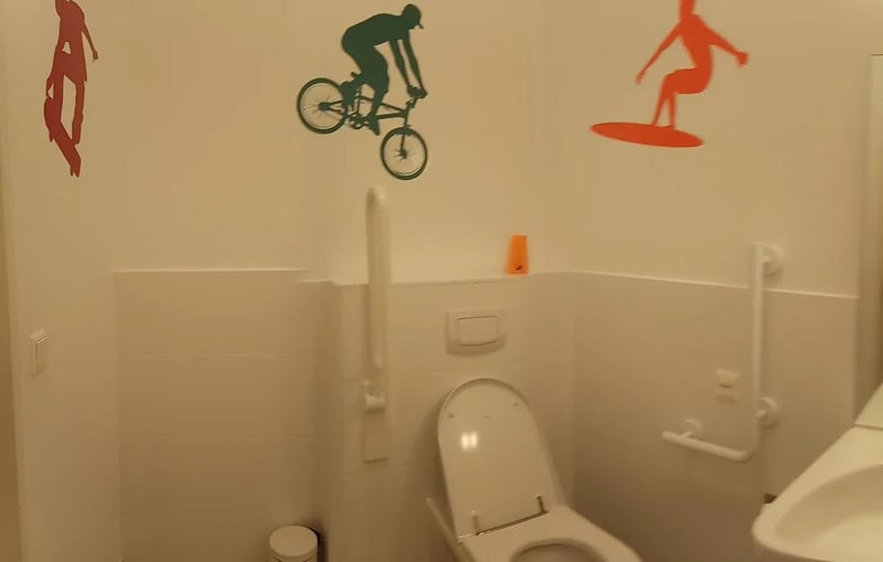 Decorative wall stickers of a skateboarder, cyclist, and snowboarder in a bathroom.