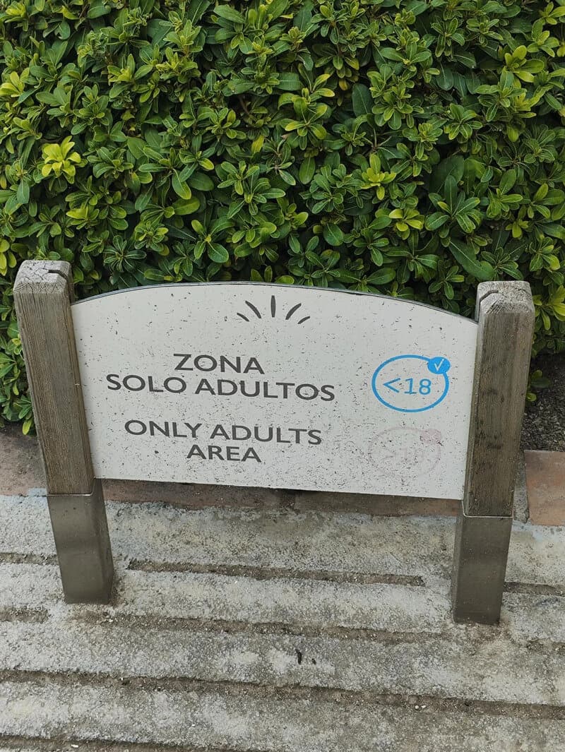 Sign reading 'Zona Solo Adultos' and 'Only Adults Area' with a '.