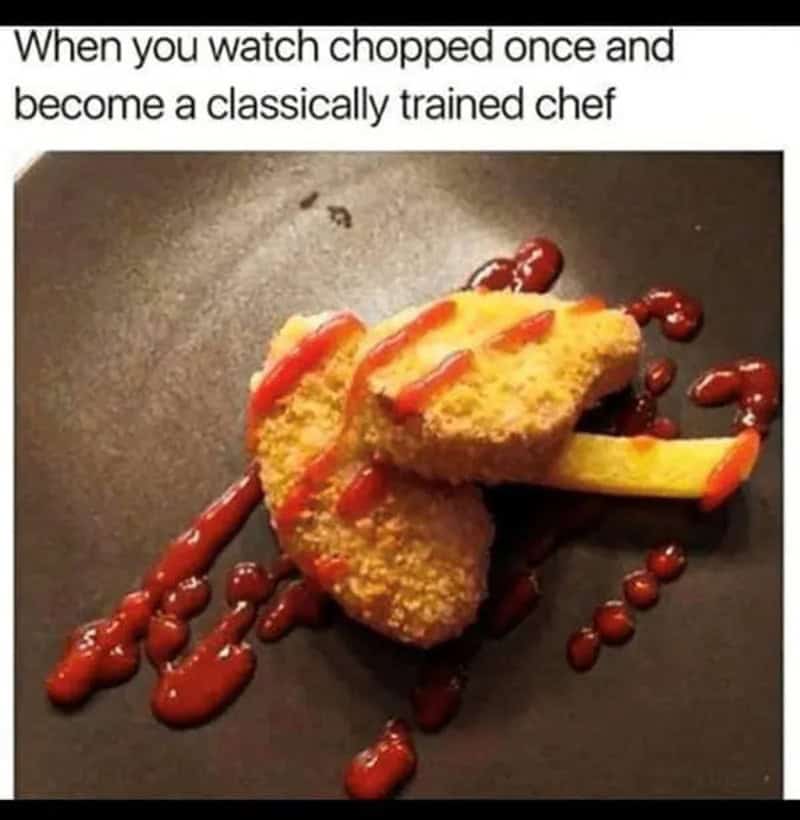 Chopped chicken with ketchup on a black plate, resembling a chef's hat.