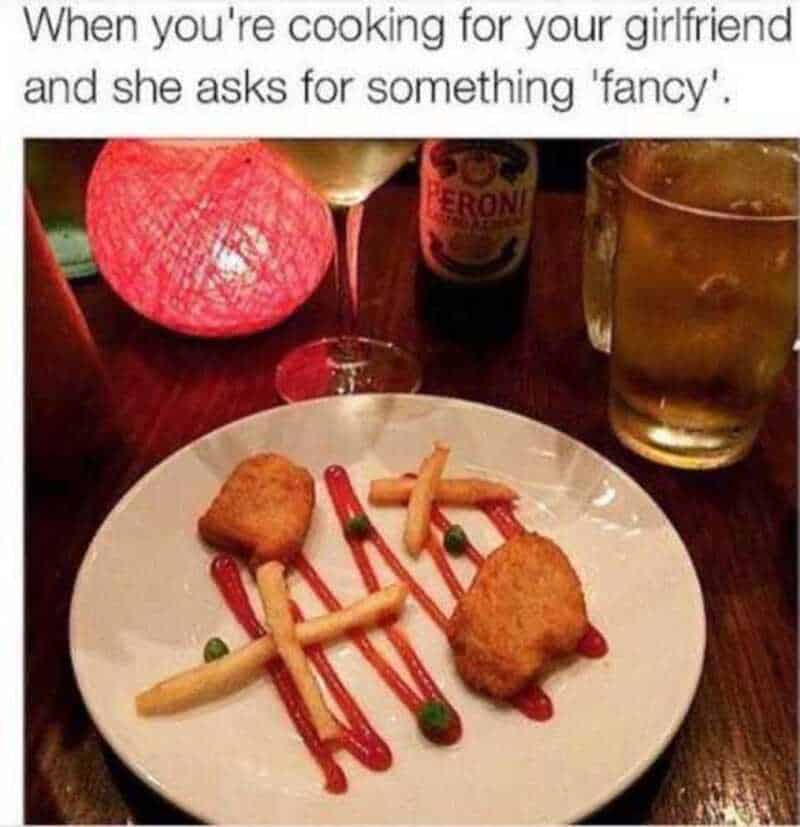 Fried food with ketchup on a white plate, drinks, and a red lamp.