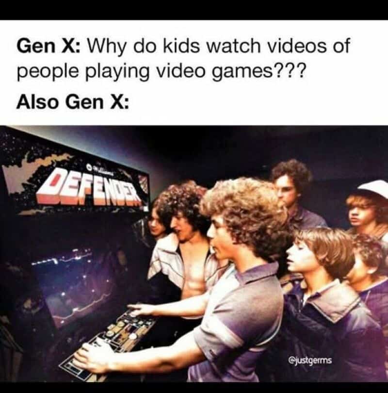 Group of kids playing video games at an arcade with 'DEFENDER' game in background.
