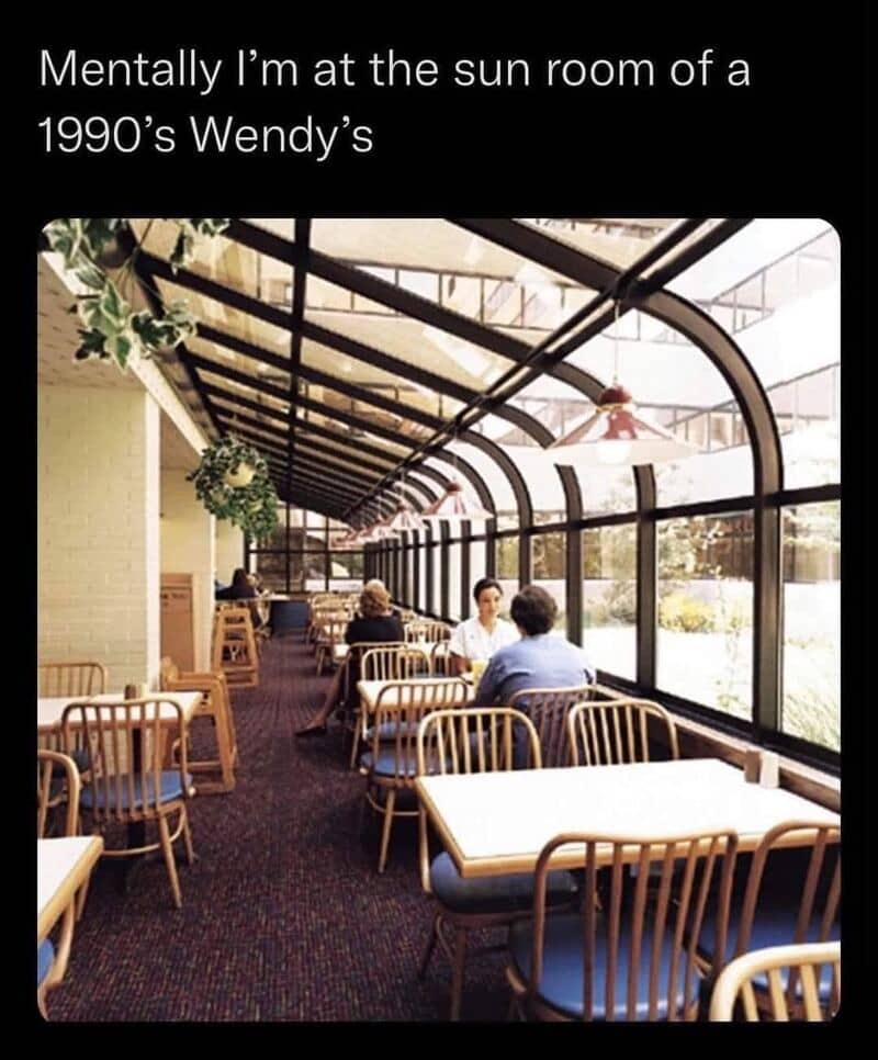 People sitting in a sunroom of a 1990s Wendy's restaurant.