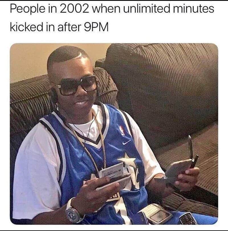 Person in 2002 with sunglasses, holding multiple phones, smiling, wearing a sports jersey.