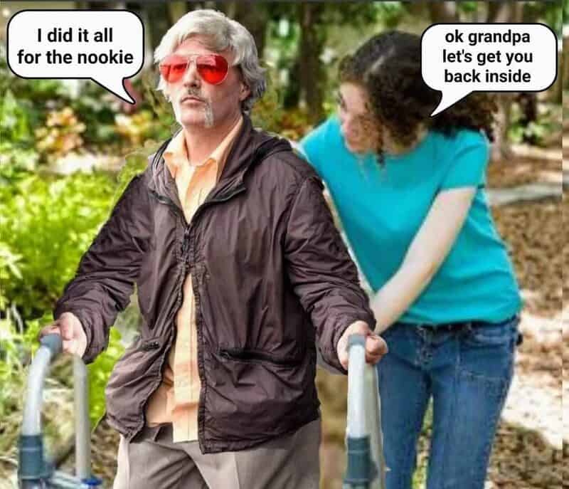 Older man with sunglasses and a walker, woman behind him, both outdoors.