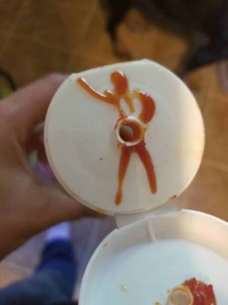 Silly figure drawn with ketchup on a milk bottle cap.