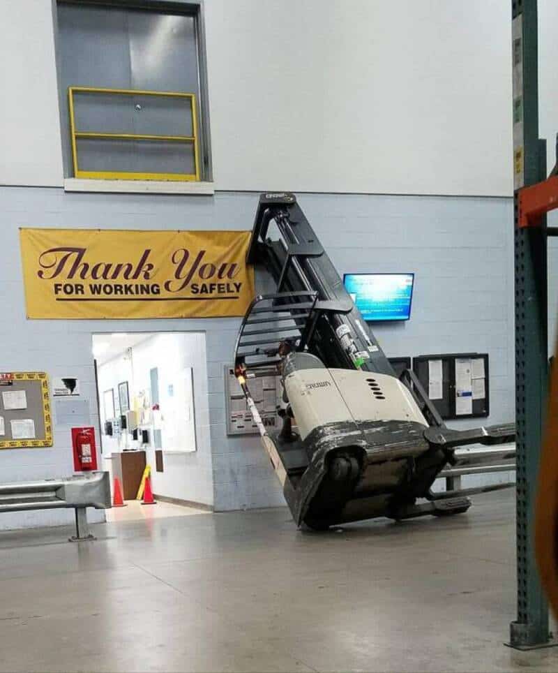 Forklift tipped over on its side in a warehouse with a 'Thank You for Working Safely' banner.