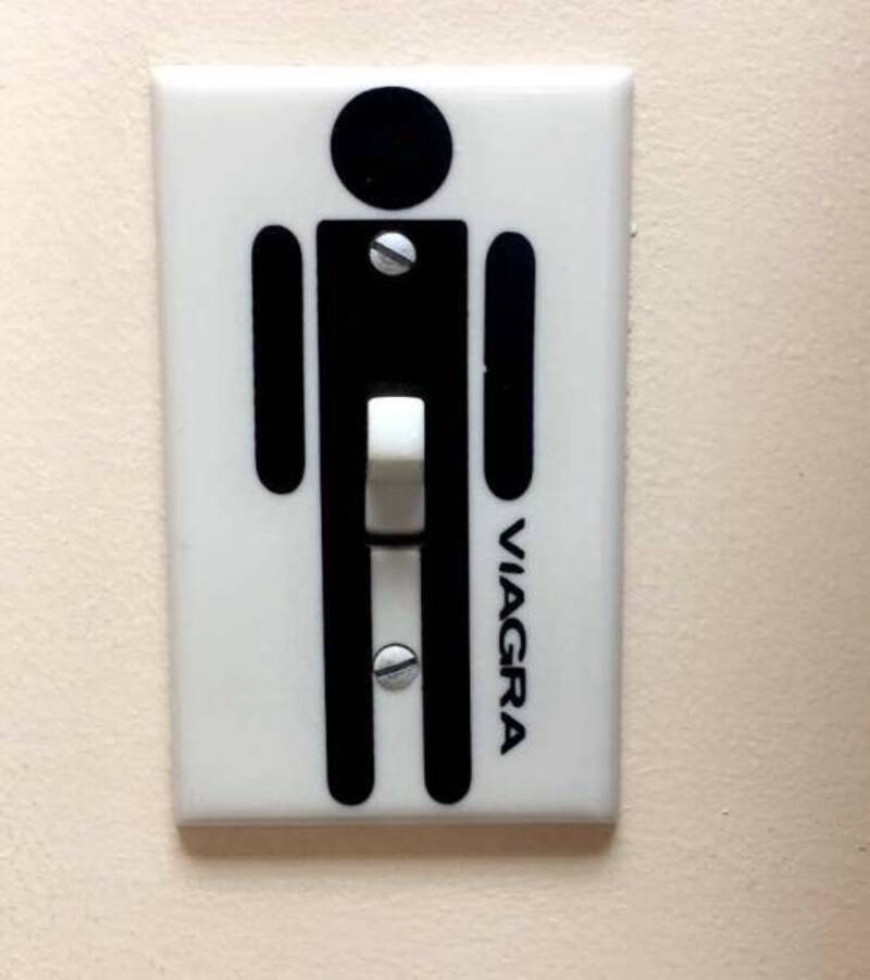 Humorous wall switch cover with a stick figure and 'VIAGRA' label.
