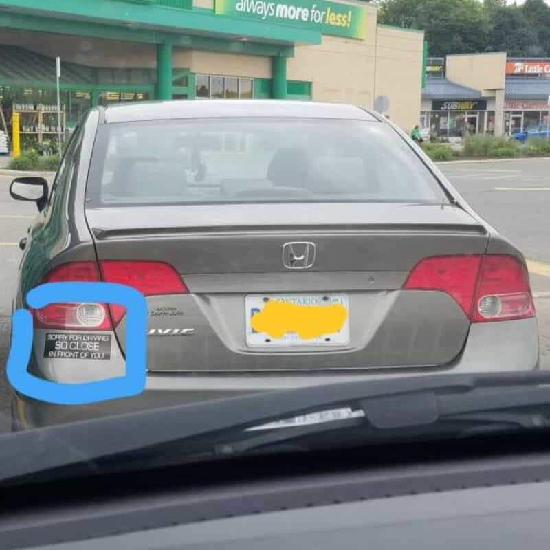 Honda Civic with a sign saying 'Sorry for driving so close in front of you' on the rear window.