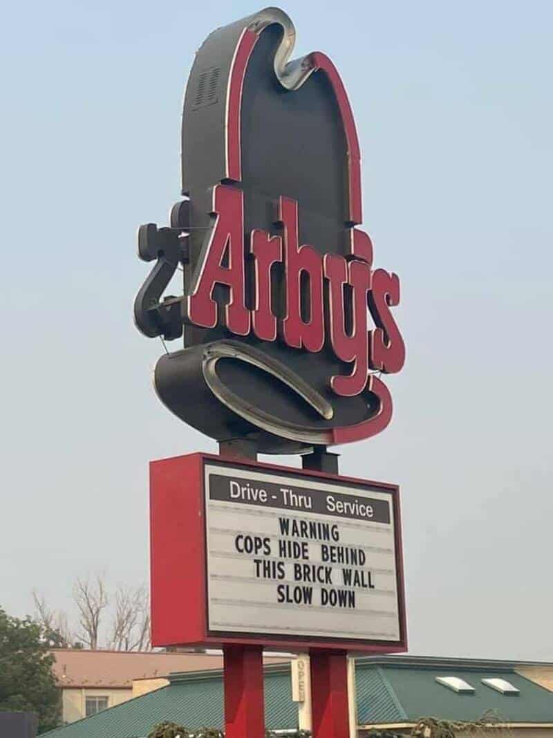 Arby's sign with a humorous warning about cops hiding behind the brick wall.