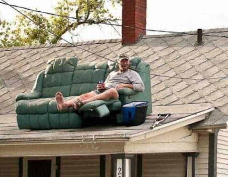 Man relaxing on a couch on the roof of a house.